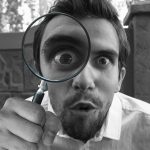 man looking through magnifying glass